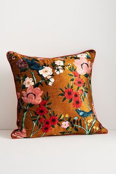 an orange floral pillow sitting on top of a white table