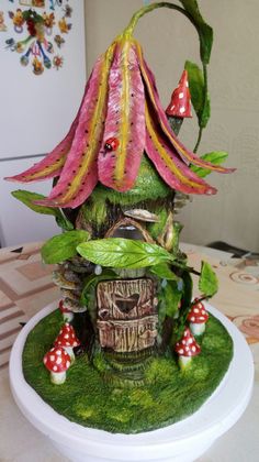 a mushroom house with flowers and mushrooms on it's roof is sitting on a table