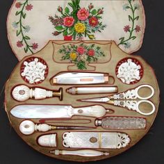 an assortment of kitchen utensils are displayed on a tray with flowers and leaves