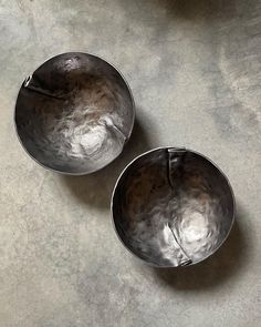 two metal bowls sitting on top of a table