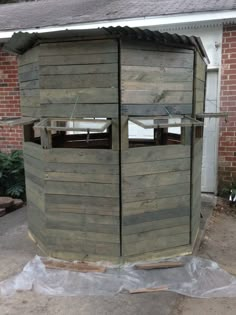 a wooden outhouse sitting in front of a brick building with plastic covering around it