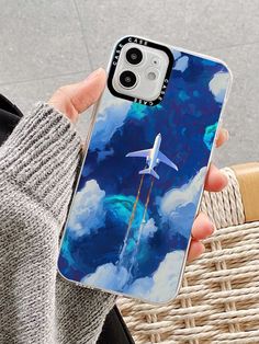 a person holding up a phone case with an image of a plane in the sky