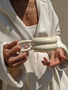 a woman wearing a white robe holding an object in her hands