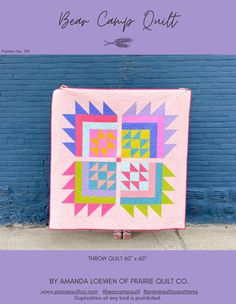 a pink quilt hanging on the side of a blue brick wall with words below it