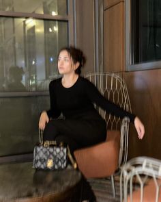 a woman sitting in a chair with a handbag