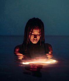 a woman with dreadlocks is in the water looking at her cell phone screen