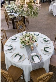 the table is set with white linens and greenery for an elegant wedding reception