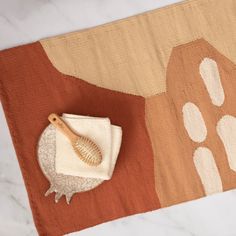 a wooden brush sitting on top of a rug next to a white and brown towel