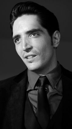 a black and white photo of a man wearing a suit with a tie on his lapel