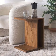 a small wooden table with a glass on it and a lamp in the corner next to it