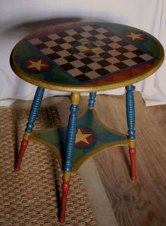 a small wooden table sitting on top of a floor next to a white wall with a checkerboard design painted on it