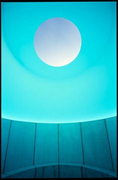 a circular light in the middle of a room with a skylight above it and wood flooring