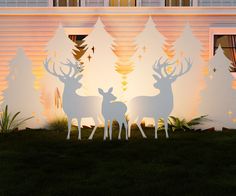 two deer standing in front of a building with trees cut out of it's sides