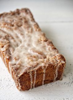 a loaf of cinnamon bread with icing sitting on top of a white tablecloth