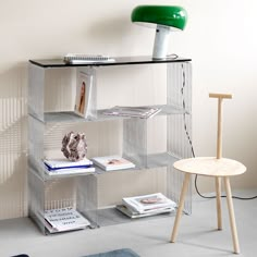 a metal shelf with books on it next to a chair and lamp in the corner