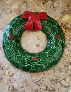 a green wreath sitting on top of a counter next to a red bow and ribbon