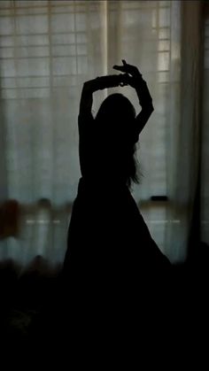 the silhouette of a woman standing in front of a window