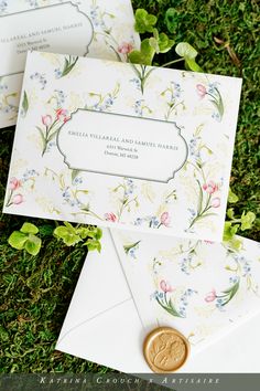 wedding stationery and envelopes on the ground with greenery in the foreground