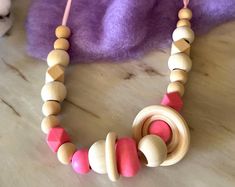 a wooden bead necklace on a table next to a stuffed animal and purple blanket