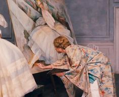 two women in white dresses are painting on a easel