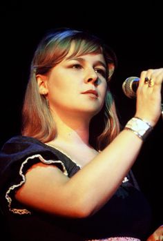 a woman holding a microphone in her right hand