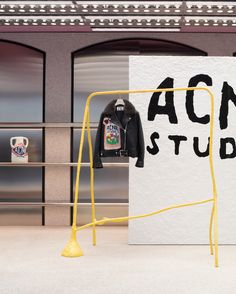 an acne studio sign with a jacket hanging on it's rack in front of a building