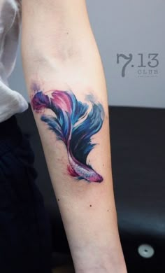 a colorful feather tattoo on the arm