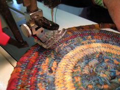 someone is using a sewing machine to sew on a colorful piece of cloth that has been made into a rug