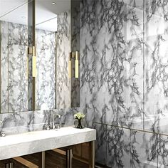 a bathroom with marble walls and flooring, two sinks and a large mirror on the wall