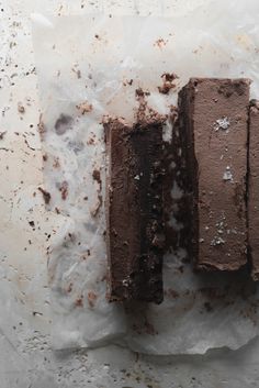 two pieces of chocolate cake sitting on top of paper