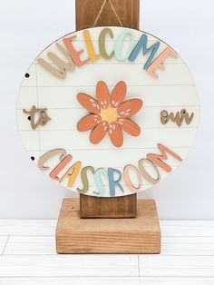 a wooden sign with the words welcome to classroom written in multicolored letters on it