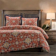 a bed with red and blue comforters in a bedroom next to a night stand