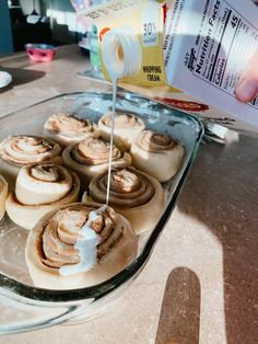 someone is pouring milk on some pastries in a glass dish