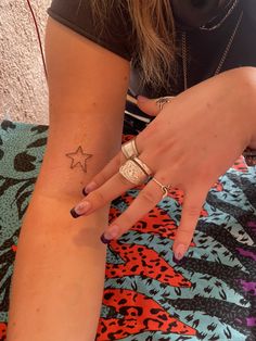 a woman with a star tattoo on her left arm and right hand is sitting down