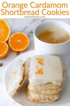 orange cardamom shortbread cookies with icing on a plate next to a cup of coffee