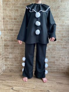 a person standing in front of a brick wall wearing black and white pom poms