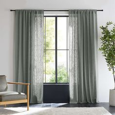 a living room with a chair, window and potted plant