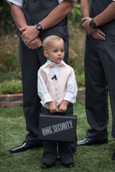 a little boy in a tuxedo holding a briefcase with the words ring security written on it