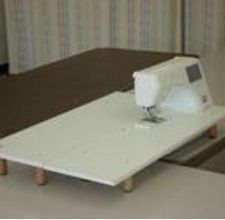 a white sewing machine sitting on top of a wooden table next to a wall with striped curtains