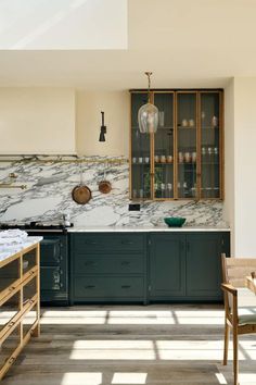 a kitchen with marble counter tops and green cabinets, along with wooden dining room chairs