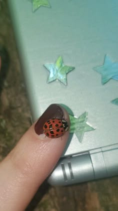 a ladybug sitting on top of a laptop computer with stars around her finger