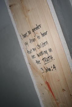 a piece of wood with writing on it in the corner of a room next to a wall