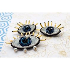 three pairs of blue and white beaded evil eye earrings on top of a table