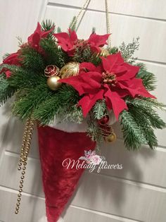 a christmas decoration hanging from the side of a garage door with poinsettis and greenery