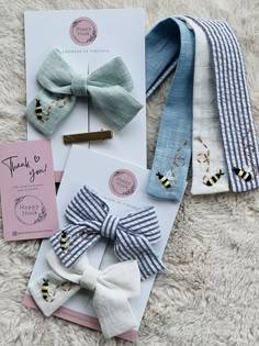 four different types of bow ties on top of a white blanket next to a card