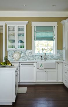 a kitchen with wooden floors and white cabinets, blue glass tile on the backsplash