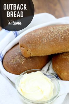 two loaves of bread sitting on top of a white cloth next to a bowl of butter