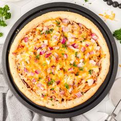 a pizza sitting on top of a pan covered in cheese and toppings next to other food