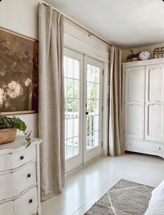 a bedroom with white furniture and large windows