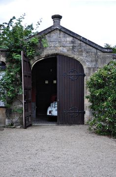 a car is parked in the entrance to an old building with vines growing around it